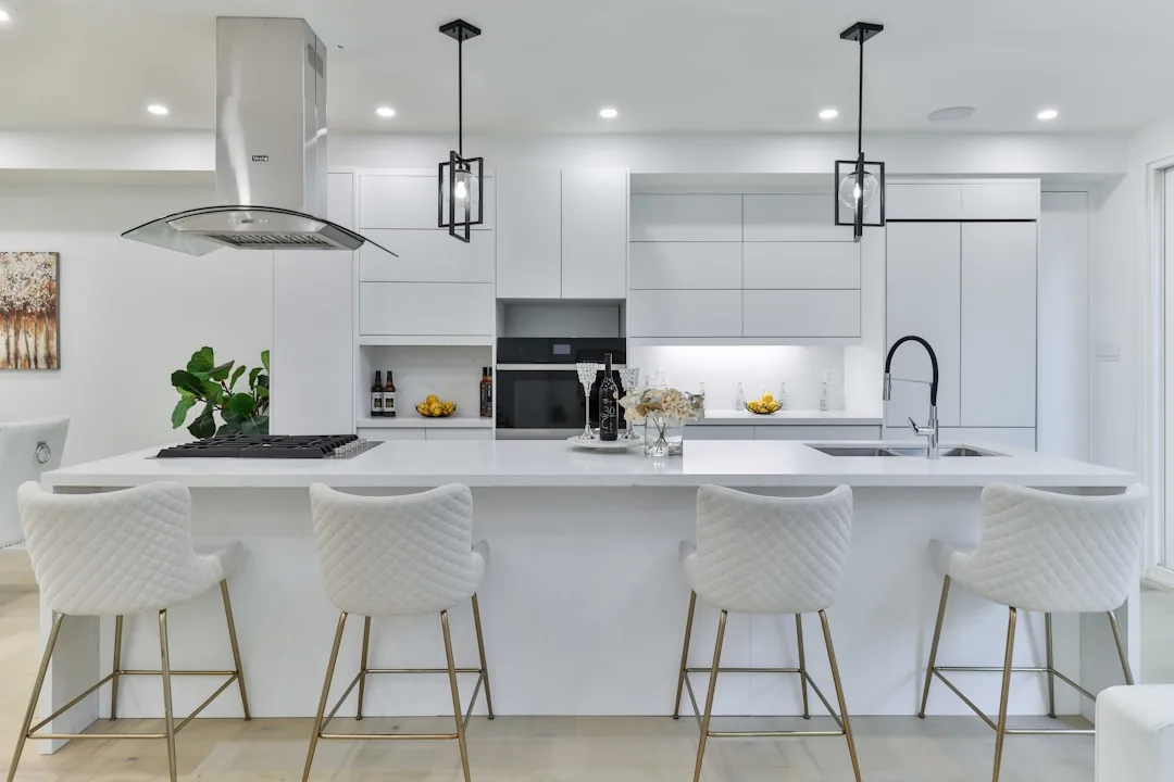 Bright white kitchen with a marble island, pendant lighting and upholstered stools